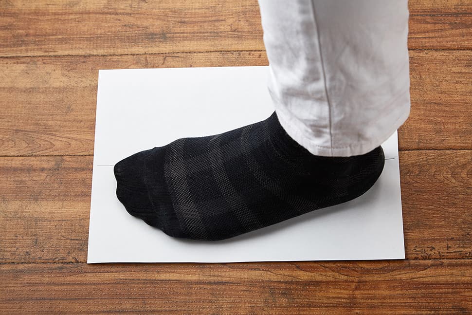 普段履いている厚みの靴下を着用し白紙の上に足を乗せます